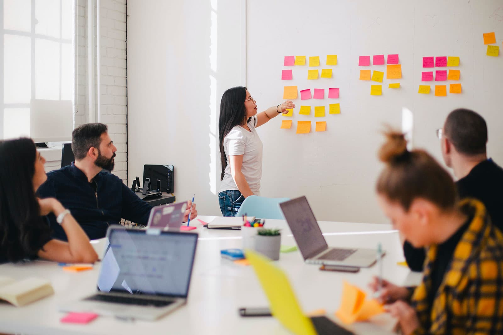 A young woman is thoughtfully placing a sticky note on a whiteboard, symbolizing clarity, planning, and productivity. With a calm expression and focused eyes, she’s mapping out ideas — one note at a time.